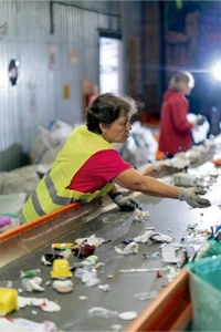 Female worker at a recycling facility working on the belt to seperate materials.